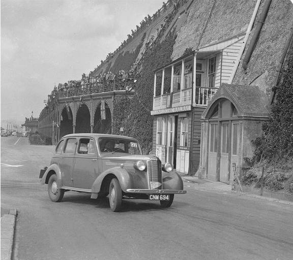 car on road by cliff with climbing plants